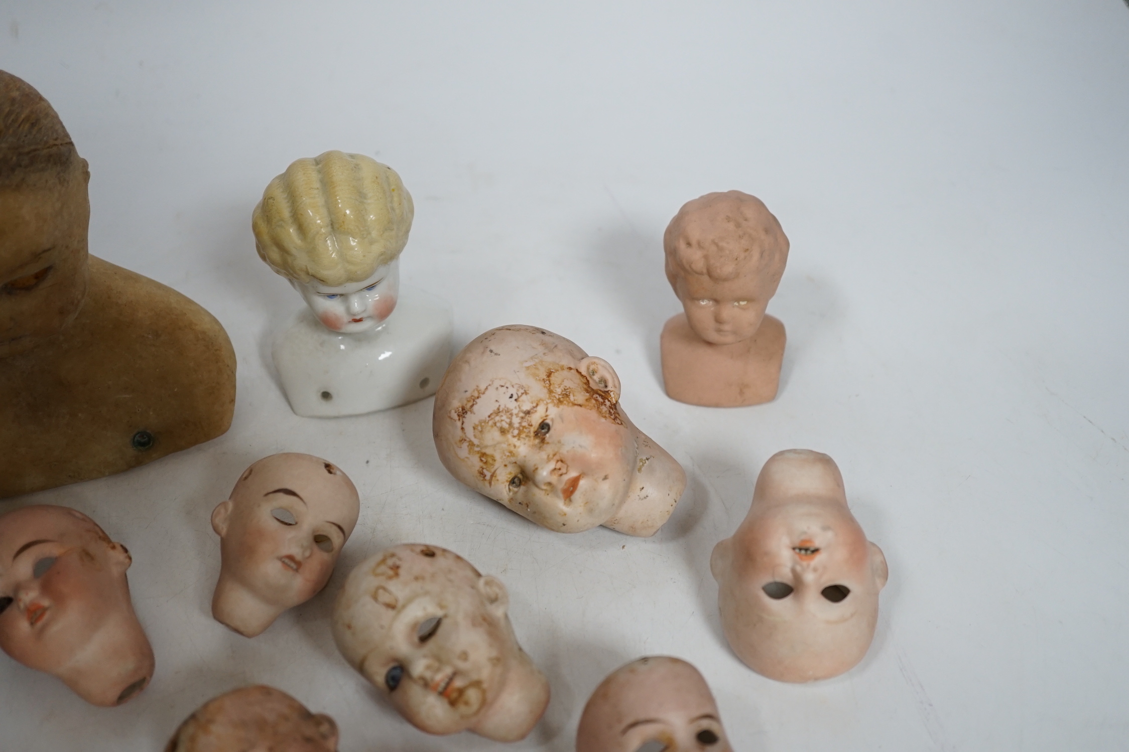 Twelve small bisque doll heads and a wax head